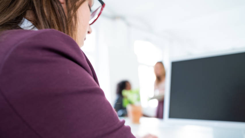 Foto de una chica en una clase vista por detrás, delante tiene una pizarra 
