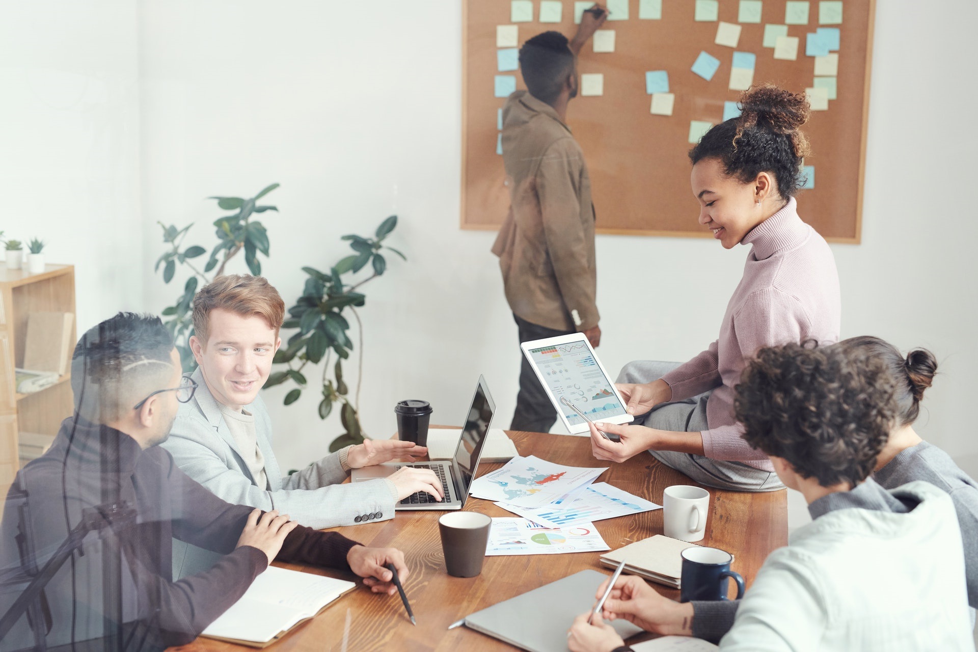 Personas trabajando en equipo junto a mesa llena de papeles.