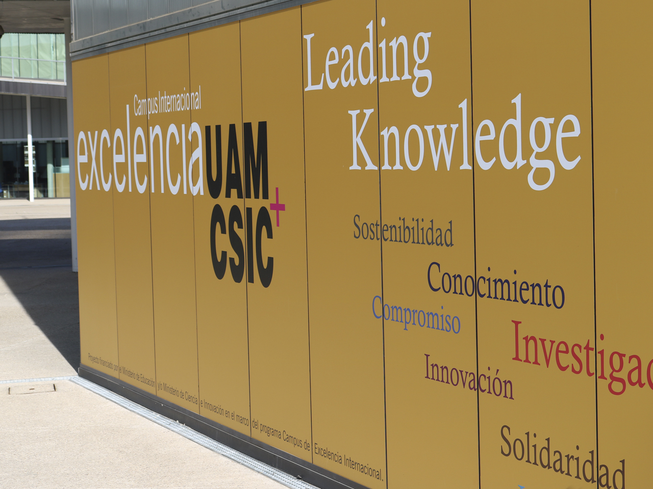 Pared amarilla con el logo del campus de Excelencia UAM-CSIC