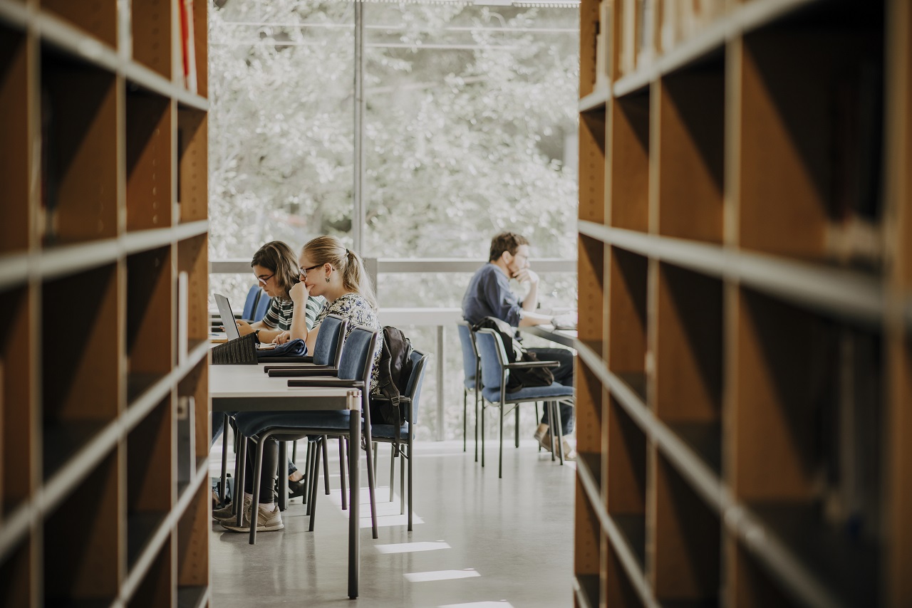 Imagen de un estudiante escribiendo en la biblioteca