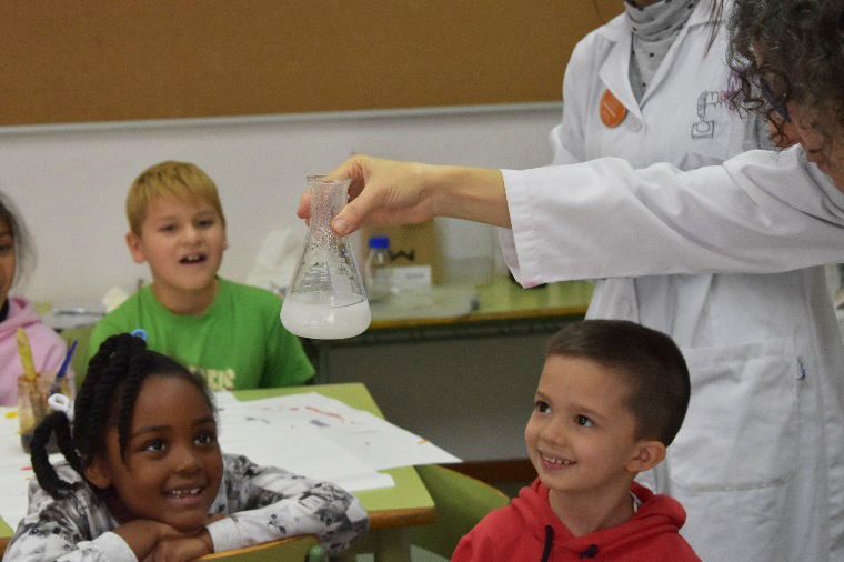 Imagen de una profesora enseñando química a niños.