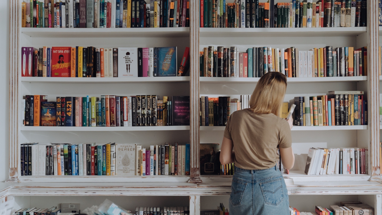 Imagen de una chica consultando una estantería de libros