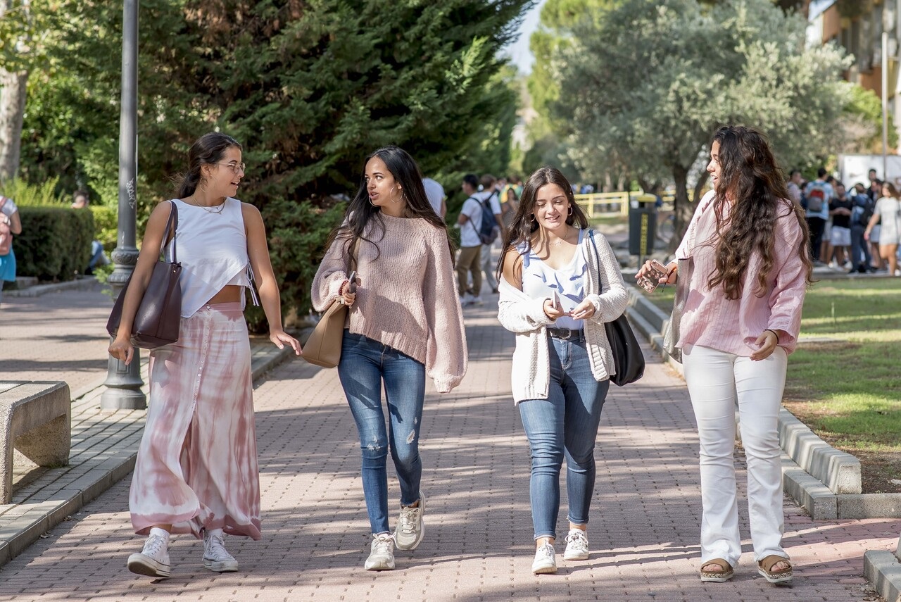 Cuatro estudiantes caminan por el campus mientras charlan animadamente