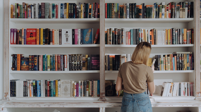 Imagen de una chica buscando un libro en una estantería