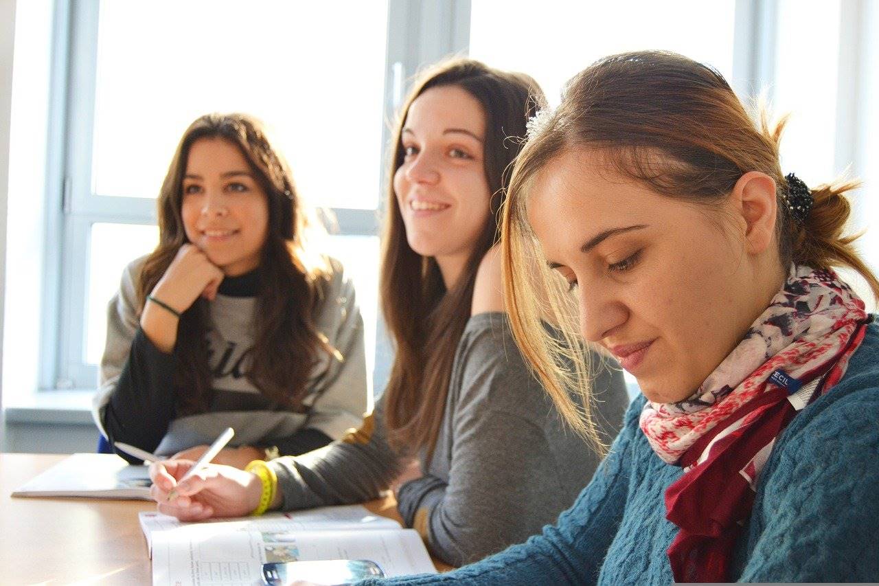 Tres estudiantes escuchan atentamente a un interlocutor (fuera de plano) 