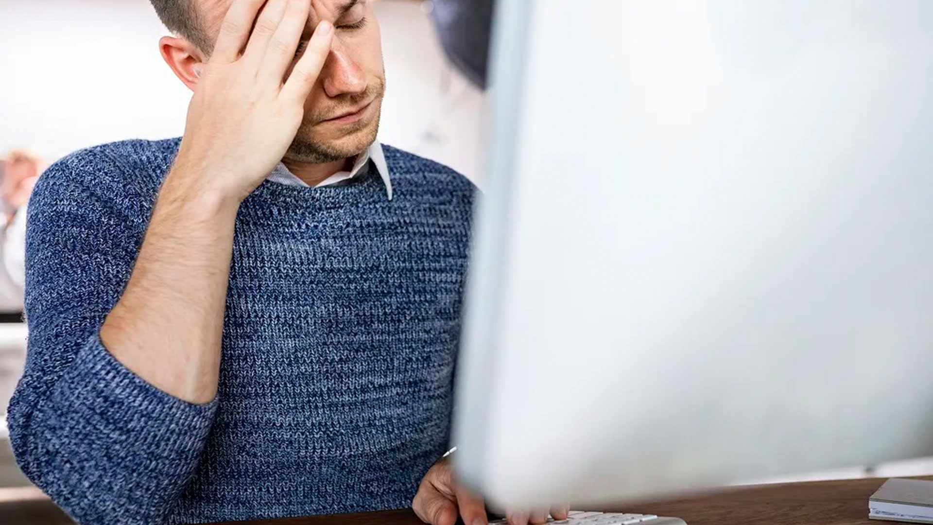 Un hombre muestra signos de estrés delante de un ordenador.