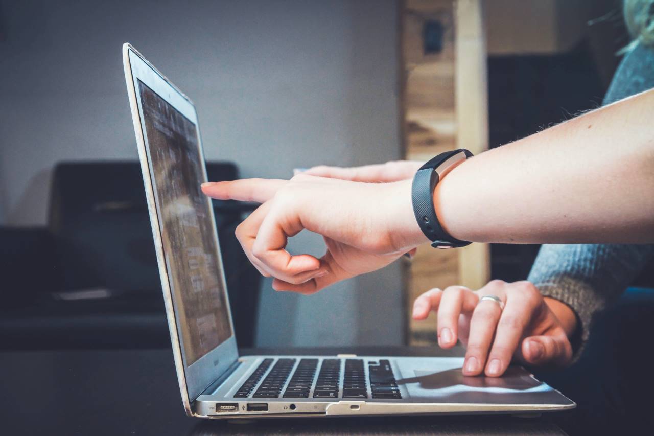 Imagen de dos manos de distintas personas trabajando en un proyecto en un portátil.