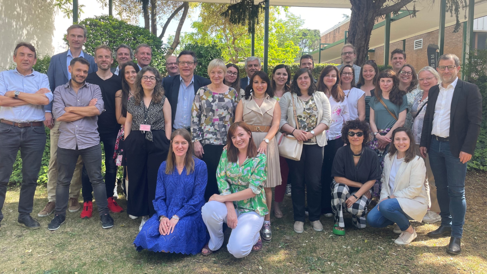 Fotografía de grupo de diferentes edades y sexos de pie delante de la cámara posando.