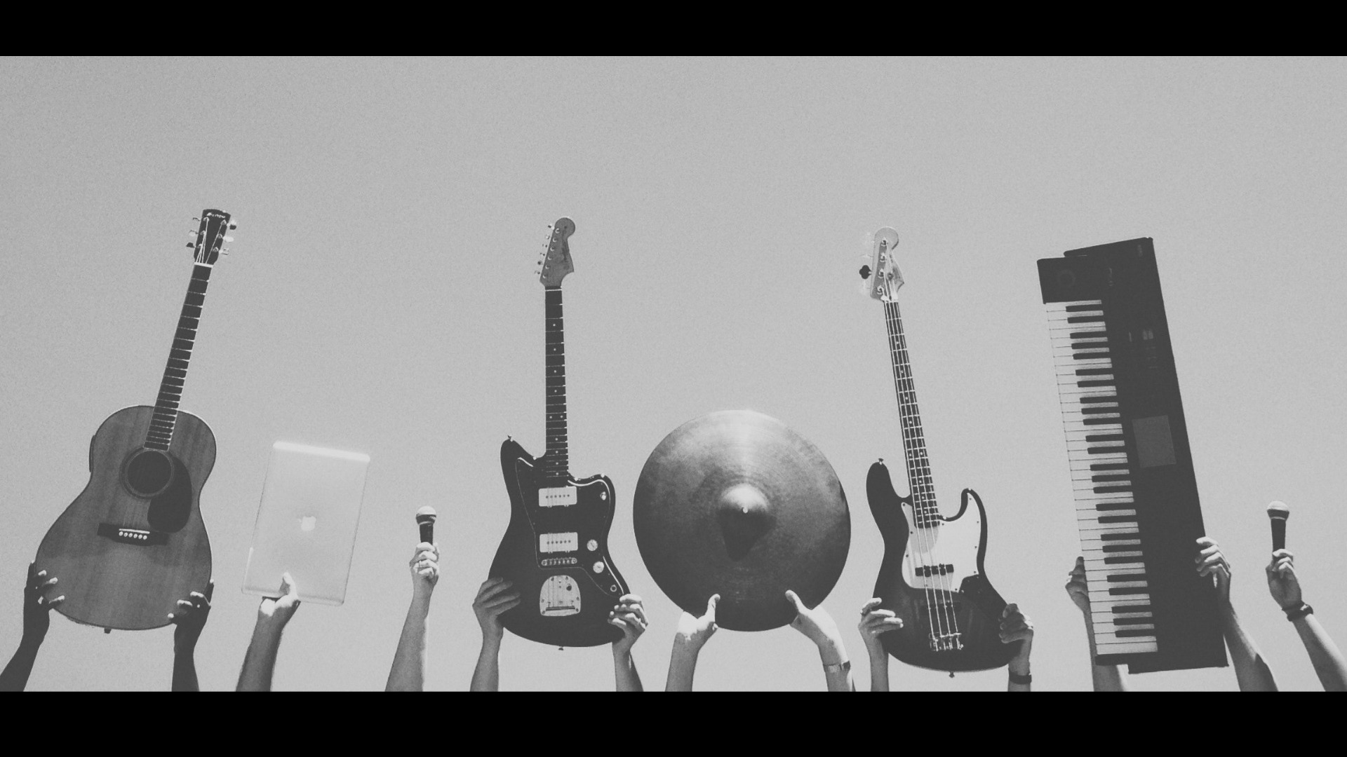 Fotografía en blanco y negro de manos alzando instrumentos.