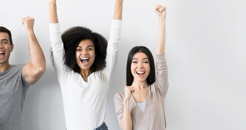 Emprendedores sonriendo y celebrando con los brazos hacia arriba.