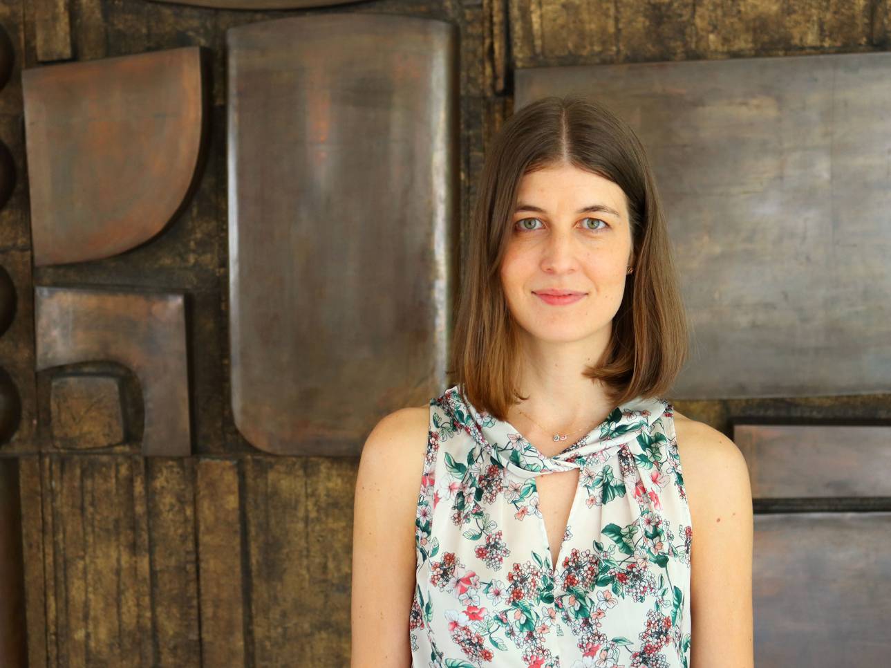 La investigadora Ana Cueto posa delante de un mural en el hall de la Facultad de Ciencias de la UAM.