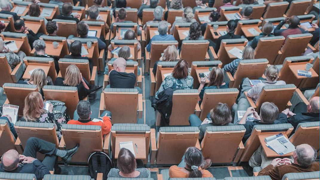 grupos de personas sentadas en salon de actos