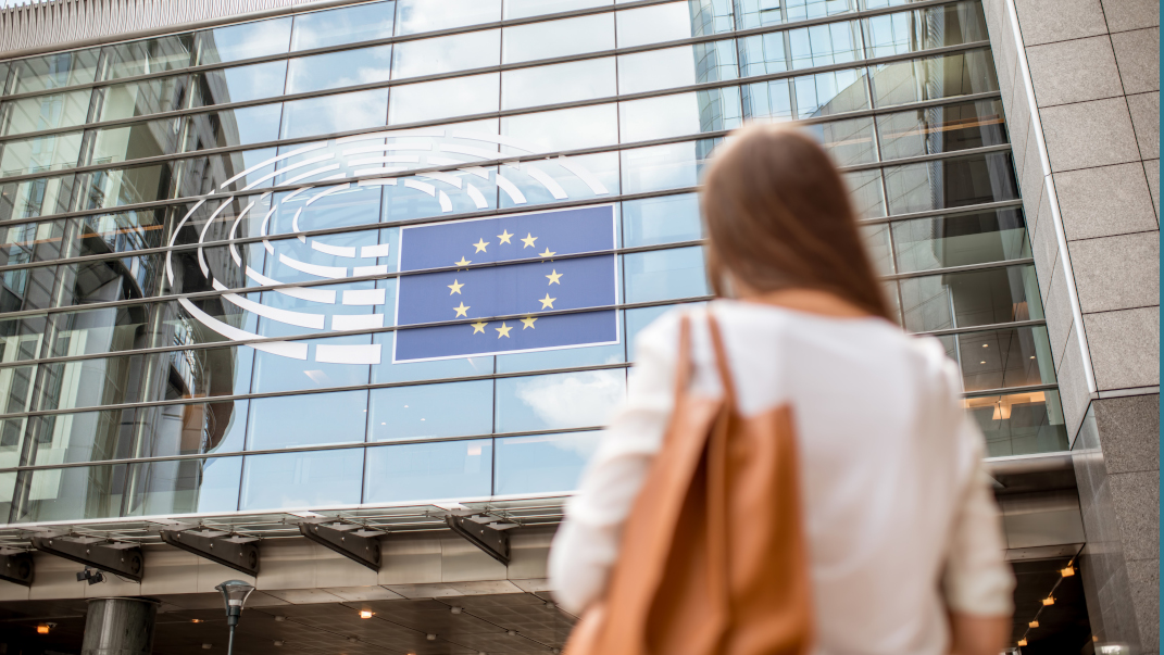 mujer frente a edificio de cristal con bandera europea