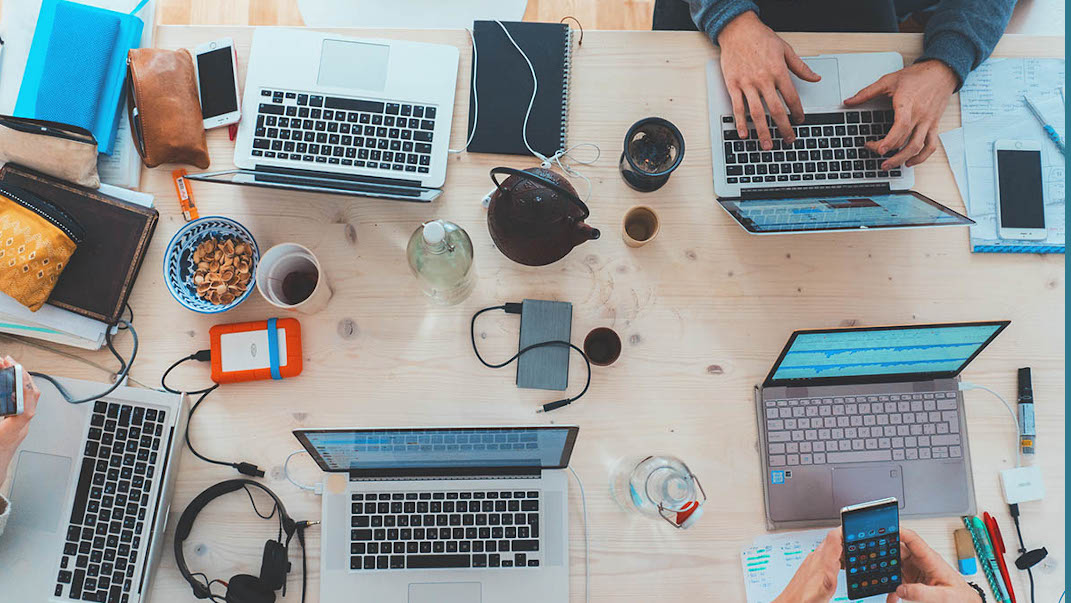 manos de personas y portátiles sobre una mesa