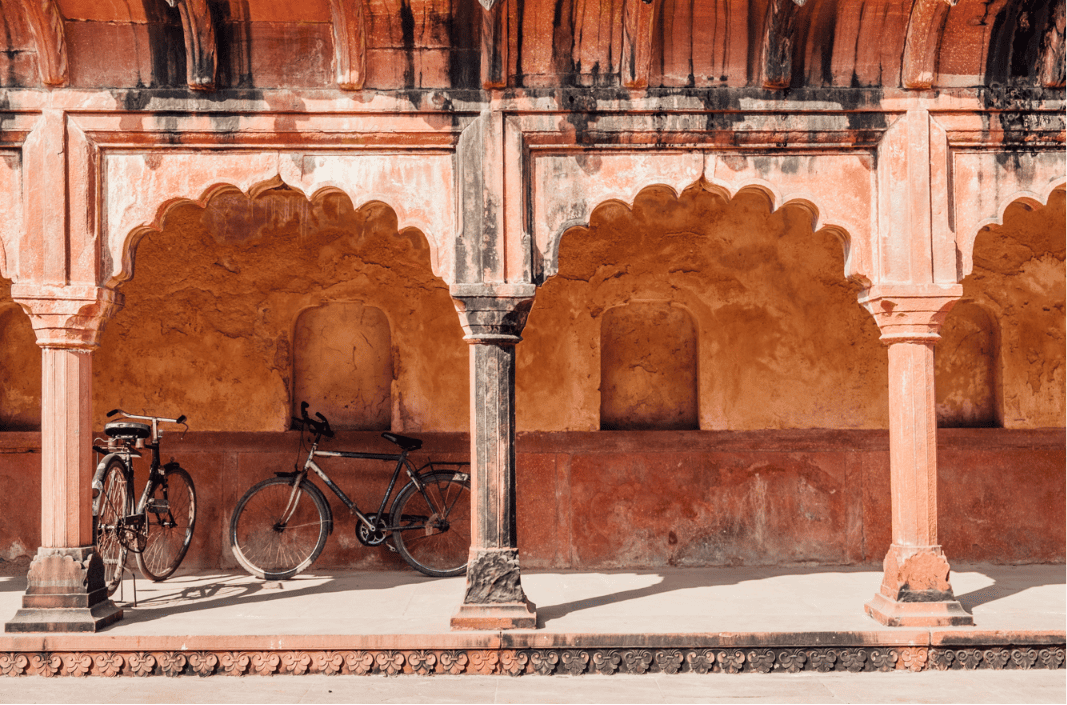 Un par de bicicletas apoyadas en una pared de un edificio hindú