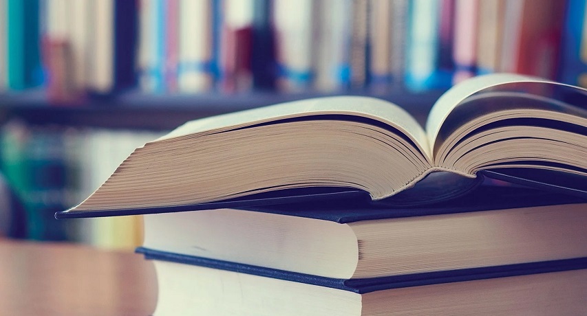 Un libro abierto sobre otro cerrado encima de una mesa