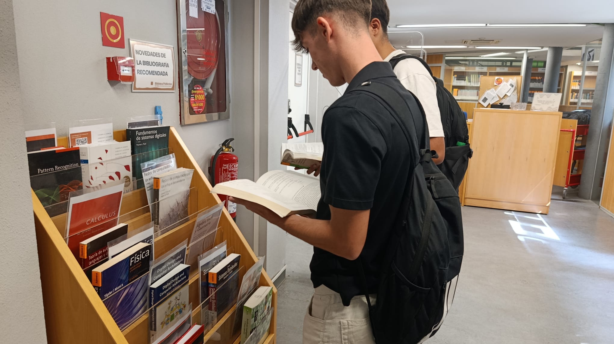 Alumnos consultando la Bibliografía Recomendada en el vestíbulo de la Biblioteca Politécnica.