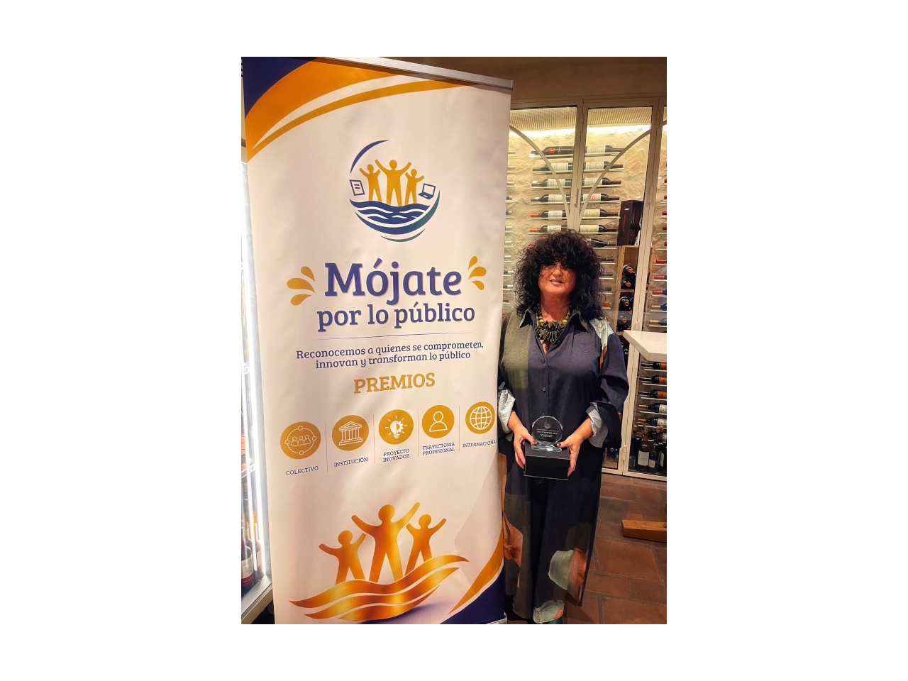 mujer mostrando premio al lado del cartel del evento